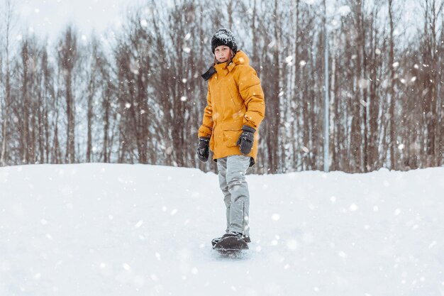 Cute teenage girl rides a snowskate in a winter park healthy lifestyle