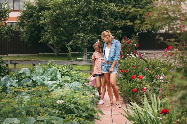 Cute teenage girl with her mother watering the flowers