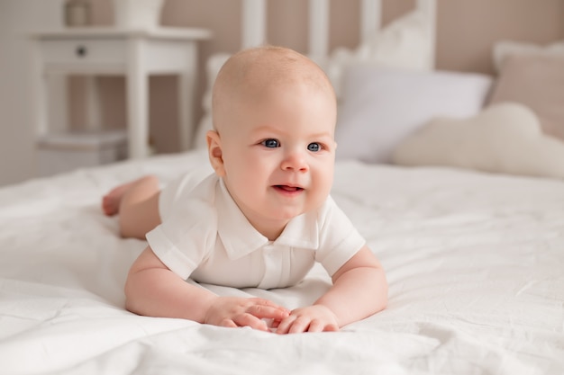 Cute toddler 6 months lies on the bed smiling