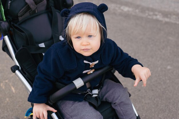 Cute toddler baby boy in a baby stroller