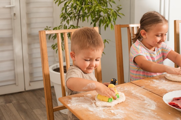 The cute toddler boy is playing while cooking