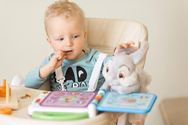 Cute toddler child eating piece of cake and drinking juice at home