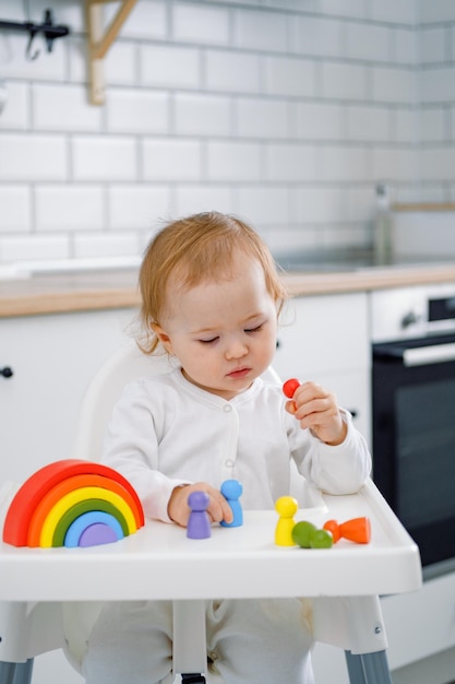 A cute toddler in a highchair playing with a wooden rainbow toy Learning colors Kid's development