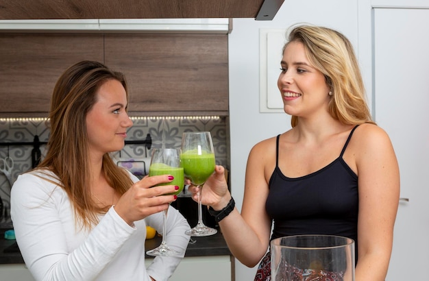 Cute vegan lesbian couple preparing spinach smoothie LGTB concept vegan people