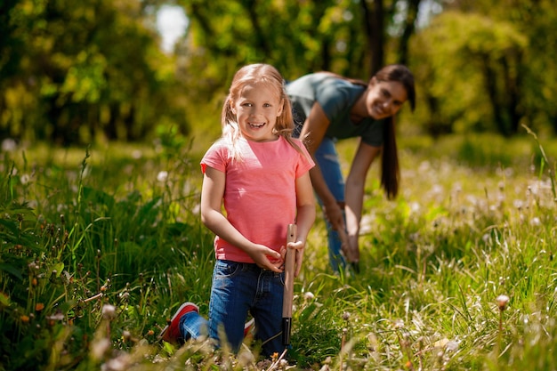 Cute woman and a blonde girl spending time in the garden and doing planting