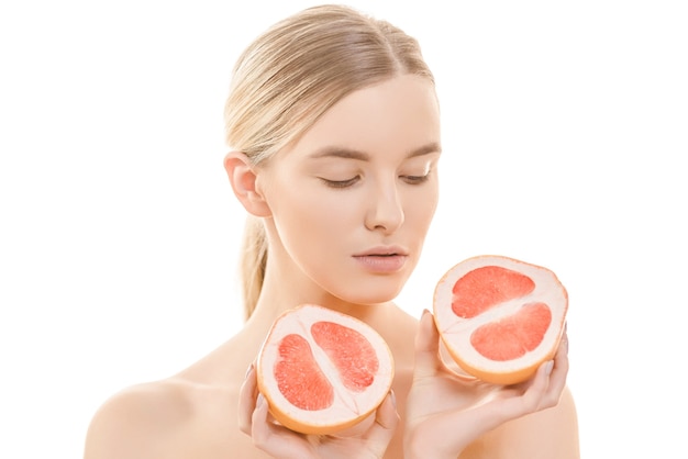 The cute woman holding a grapefruit on the white background