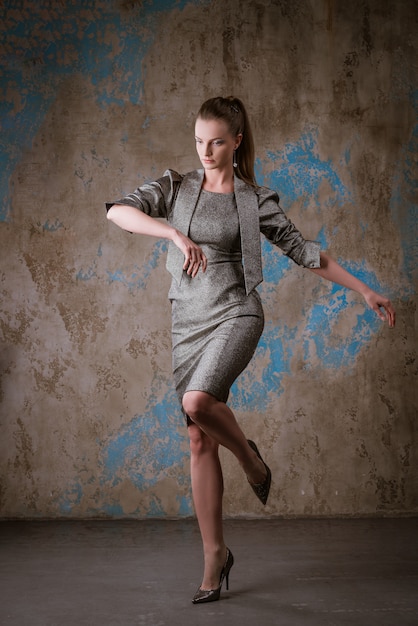 Cute woman posing in a dress on a grunge wall