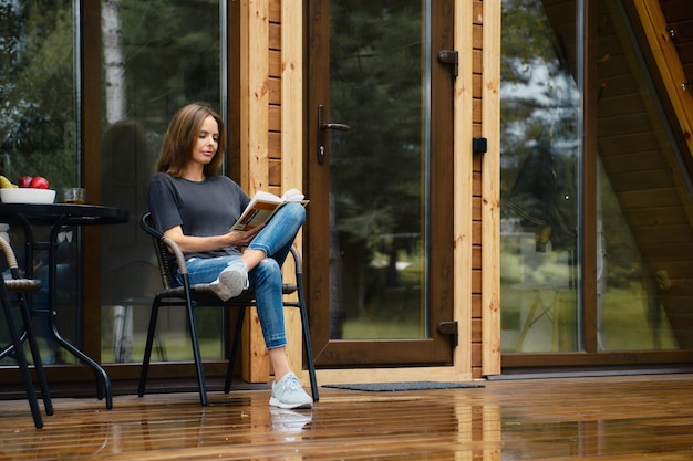 Cute woman sits on terrace and reads novel