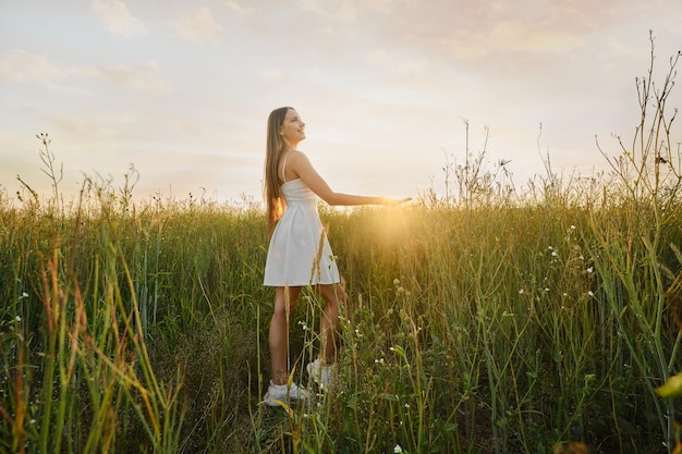 Cute woman in sundress in the field during the sunset