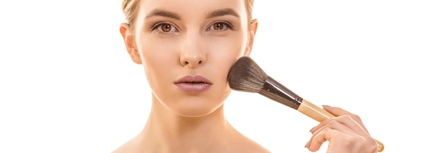 The cute woman using a cosmetic brush on the white background