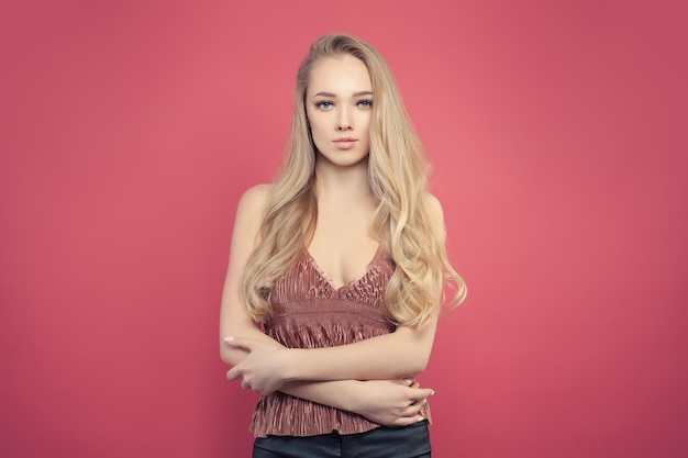 Cute woman with long blonde hair portrait on pink background