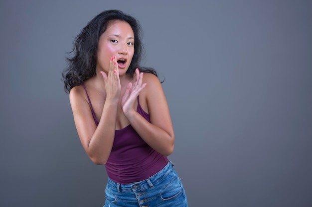 Cute young asian girl in tank top with funny expression isolated from the background