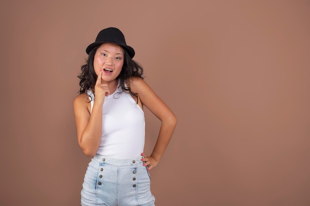 Cute young asian girl with hat making cute face isolated from the background