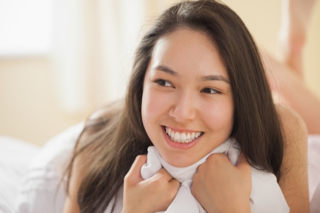 Cute young asian woman holding her duvet and smiling