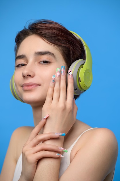 Cute young brunette listening to music using bluetooth wireless headphones