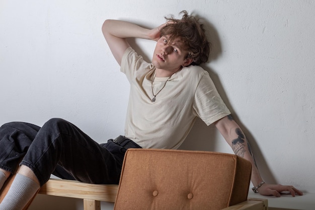 Cute Young caucasian man sitting on the top of a sofa in a lazy pose