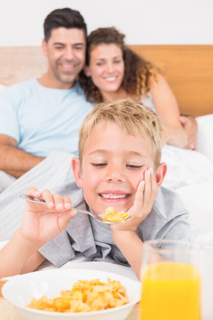 Cute young family having breakfast in bed