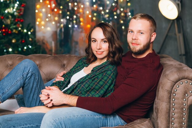 Cute young family husband and wife at the Christmas tree