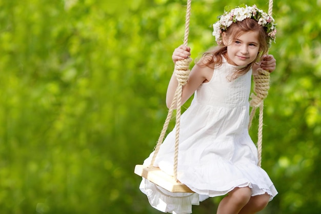 Cute young girl having fun on a swing in blossoming old apple tree garden Sunny day Spring outdoor activities for kids and enjoying Copy space