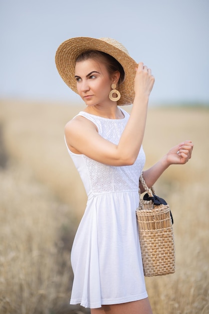 Cute young girl in a straw hat on a wheat field