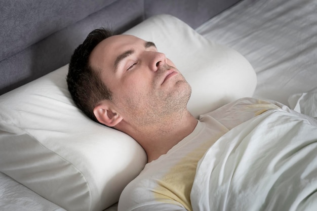 Cute young man sleeping in bed on orthopedic pillow