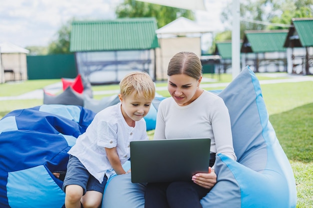 Cute young mother and son looking at laptop Happy family mother and son are resting in the park A woman on maternity leave