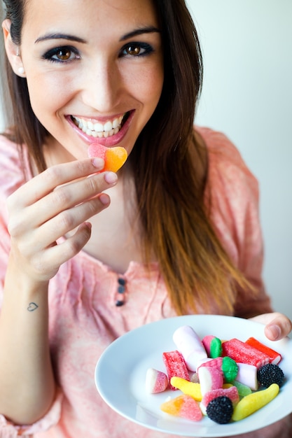 Cute young woman eating jelly candies with a fresh smile