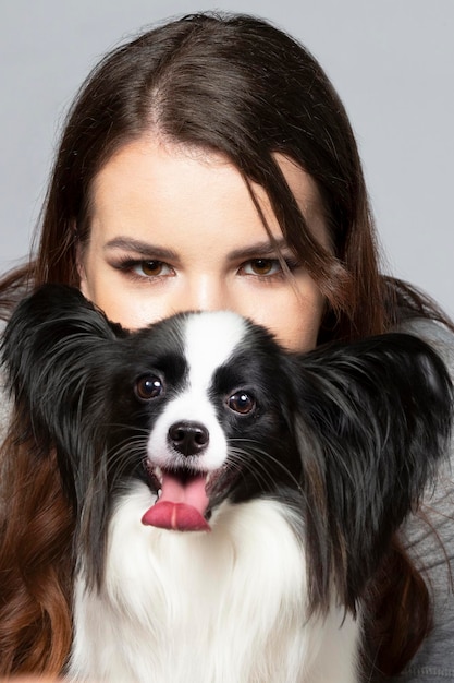 A cute young woman is hugging her papillon puppy