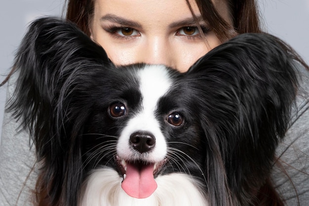 A cute young woman is hugging her papillon puppy