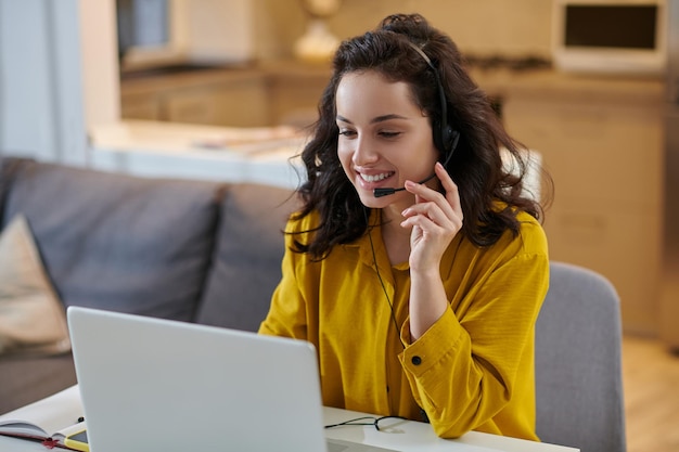 Cute young woman in a mustard shirt sitting at the laptop