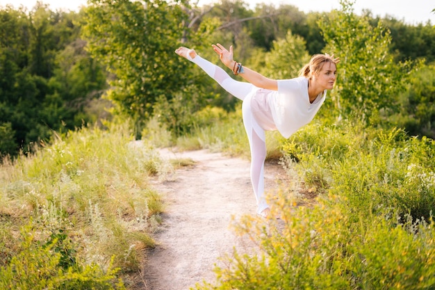 Cute young woman practicing yoga standing in Warrior three exercise Virabhadrasana III pose