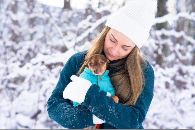 Cute, young woman in winter Warms his dog, in the cold. Girl in the snow with a Chihuahua pet, froze.