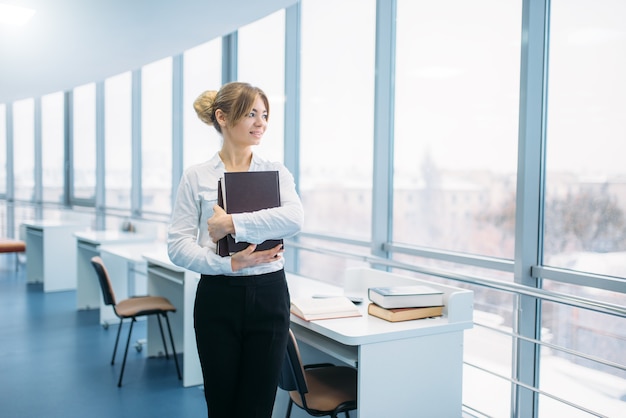 Cute young woman with book in library