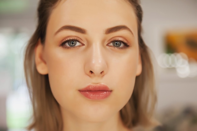 Cute young woman with perfect make-up. Close-up of face of pretty model with natural makeup