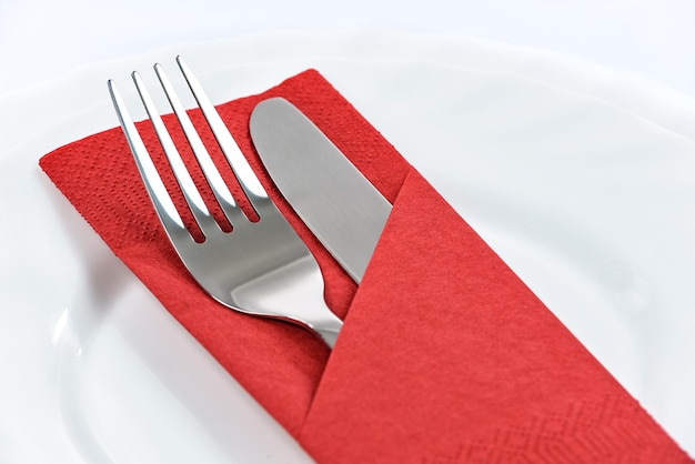 Cutlery in a red folded napkin on plates in the restaurant