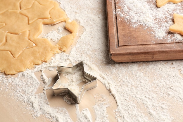 Cutter and raw dough for Christmas cookies on table