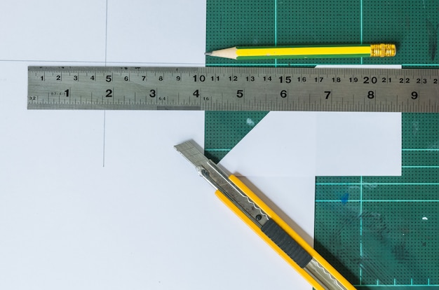 Cutter , wood pencil and ruler on old green rubber pad background