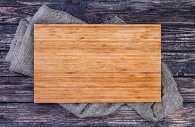 Cutting board on dark wood background, top view