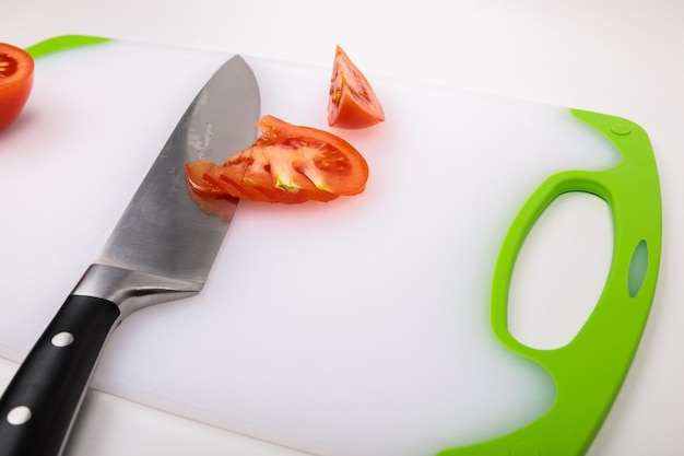 On a cutting board is a fresh red cut tomato and a large chefs knife