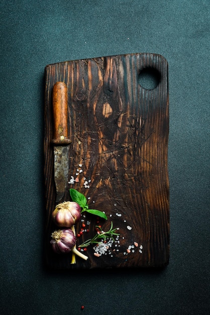 Photo cutting board rosemary and spices on an old wooden table on a dark slate background free space for the recipe