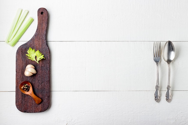 Cutting board, spice and cutlery on white wooden