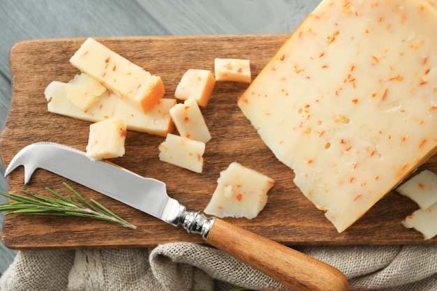 Cutting board with cheese and special knife on wooden background