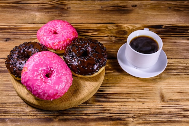 Cutting board with glazed donuts and cup of coffee on a wooden table