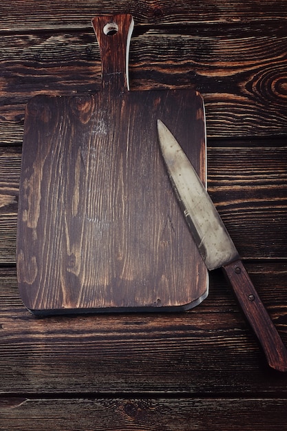 Cutting board with a knife on old wooden background