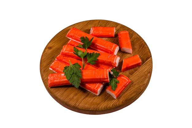 Cutting board with pile of crab sticks and parsley twig isolated on a white background