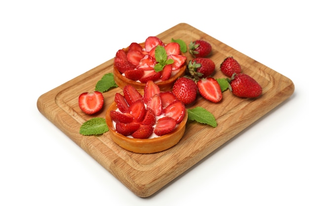 Cutting board with strawberry tarts on white background.