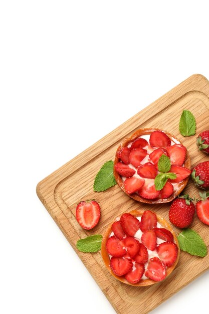 Cutting board with strawberry tarts on white background.