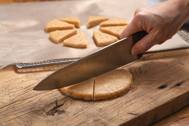 Cutting cookie dough with hand holding knife