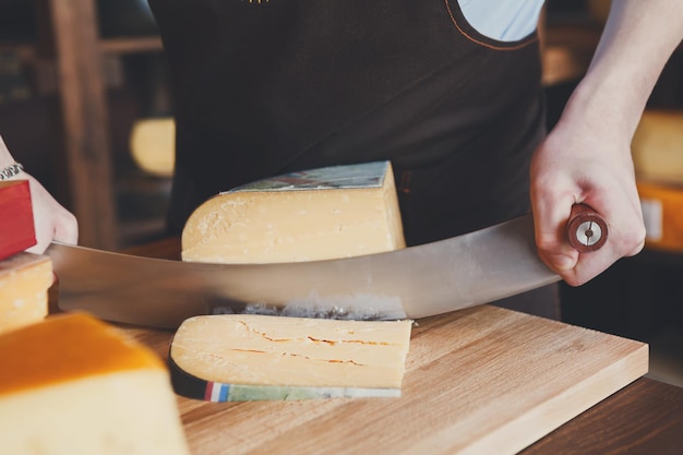 Cutting hard cheese, pecorino cheese in grocery shop, closeup