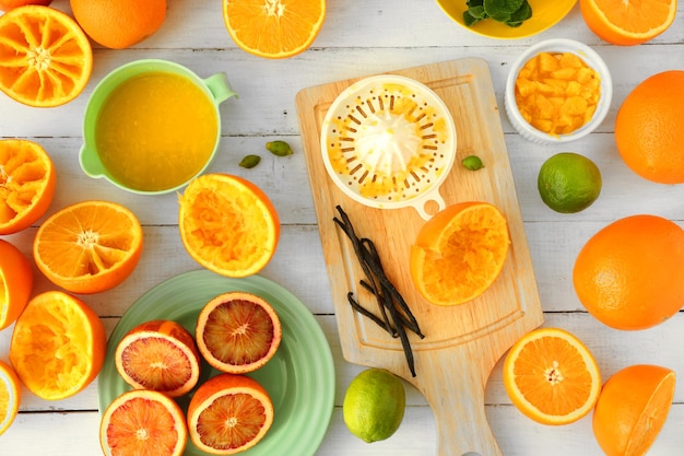 Cutting and juicing delicious oranges on white wooden table